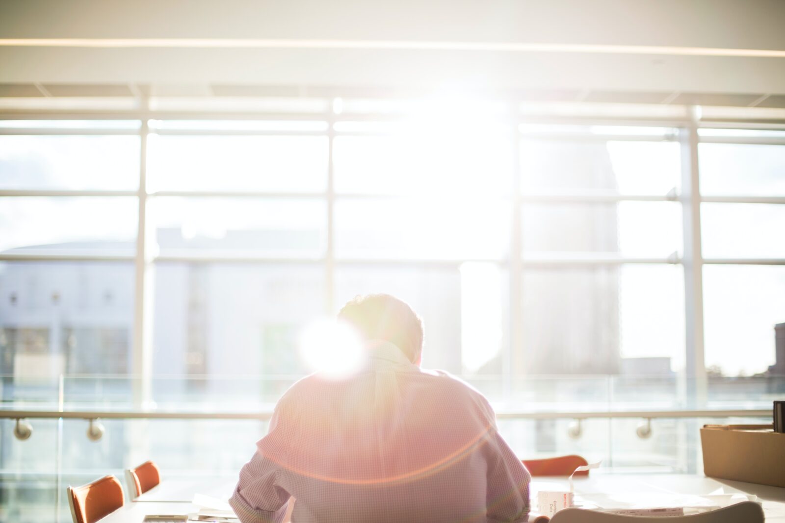 Mann sitzt in Büro mit Glassfassade